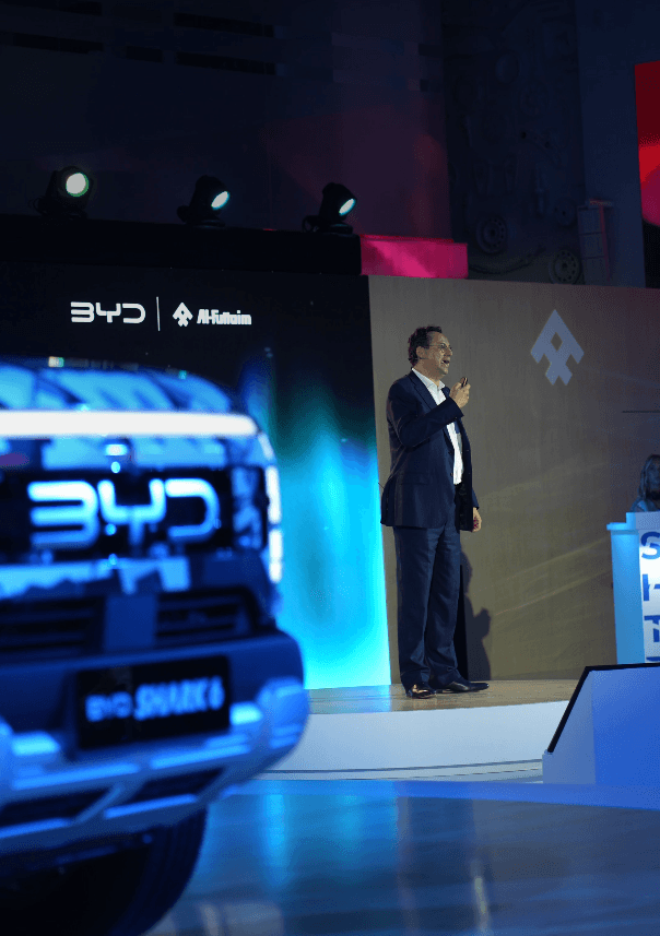 Executive presenting on a lit stage beside the product at a launch